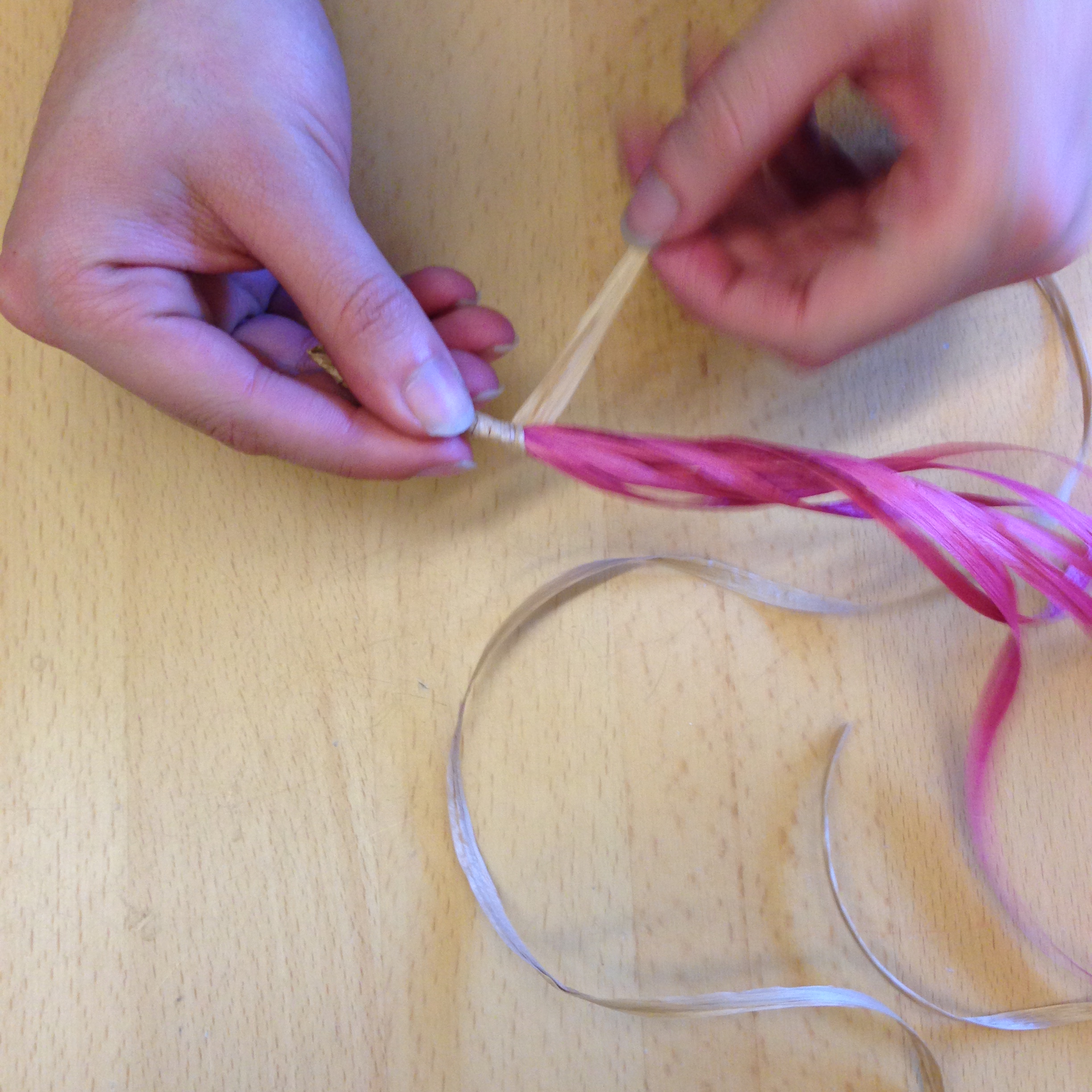 Choose a tan or black strand of raffia and wrap it tightly around the red basket core strands.