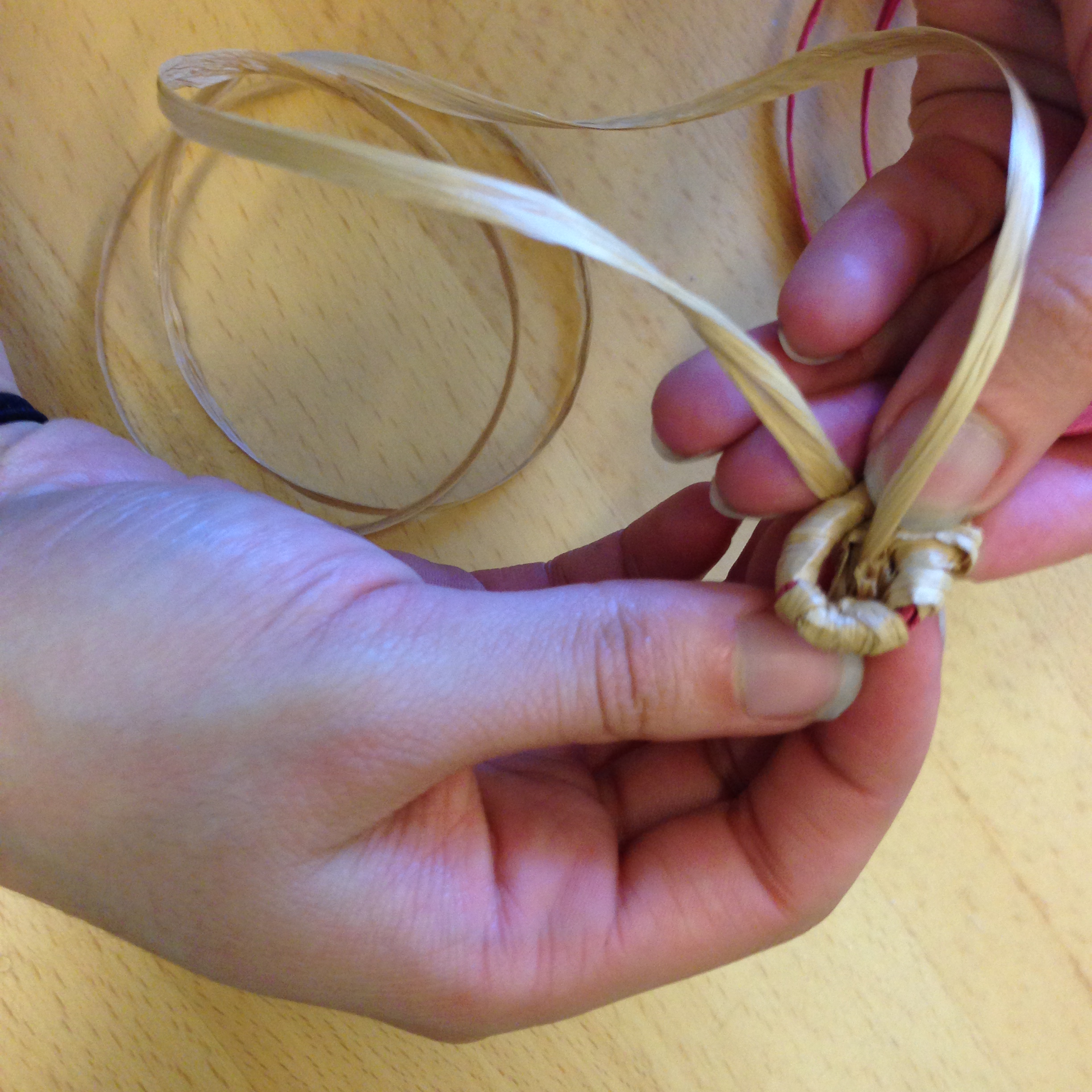 Take the end of your tan or black raffia strand and loop it through the spiral to secure the basket center.