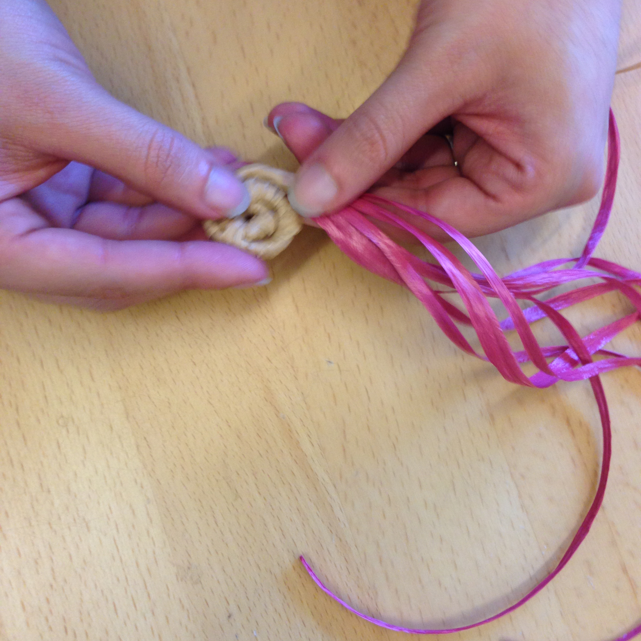 Each time you cover a few inches of the red basket core, thread your tan or black raffia through the most recent coil to keep the coils connected.